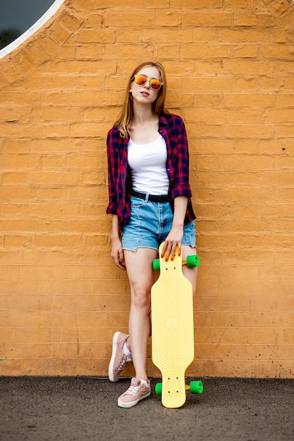 Longboarding Mädchen steht neben der Mauer