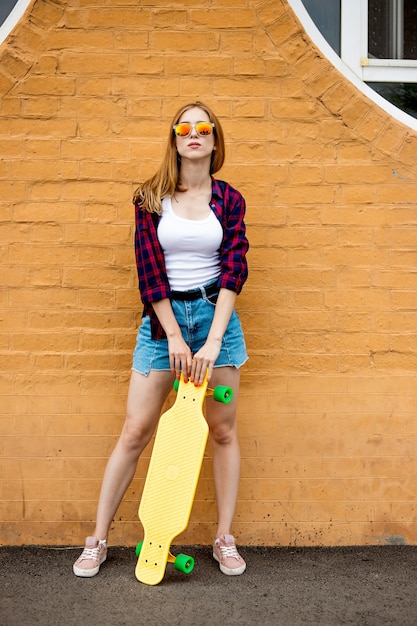 Longboarding Mädchen steht neben der Mauer