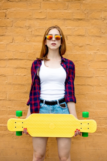 Longboarding Mädchen steht neben der Mauer