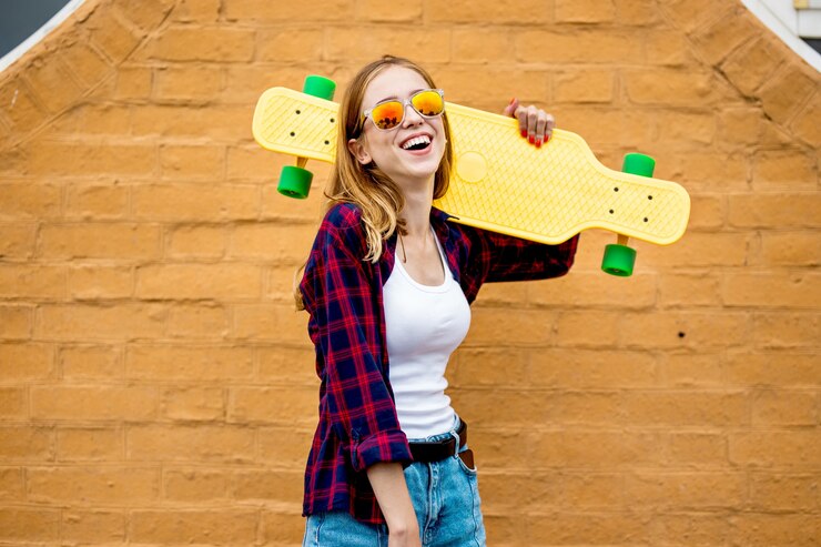 Longboarding Mädchen steht neben der Mauer