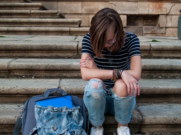 La longitud completa de una adolescente sentada en los escalones