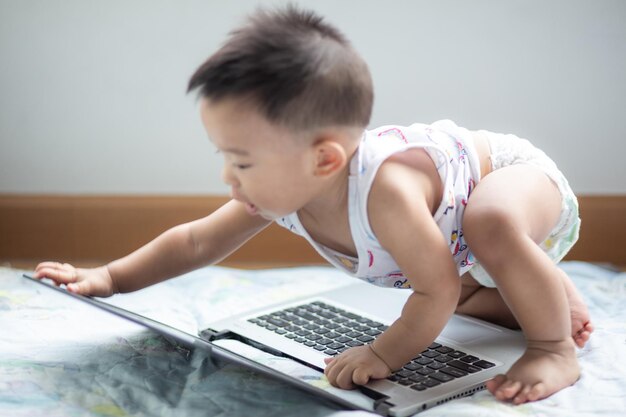 La longitud completa del bebé jugando con la computadora portátil en casa