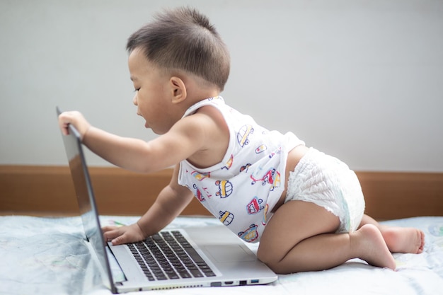 La longitud completa del bebé jugando con la computadora portátil en casa