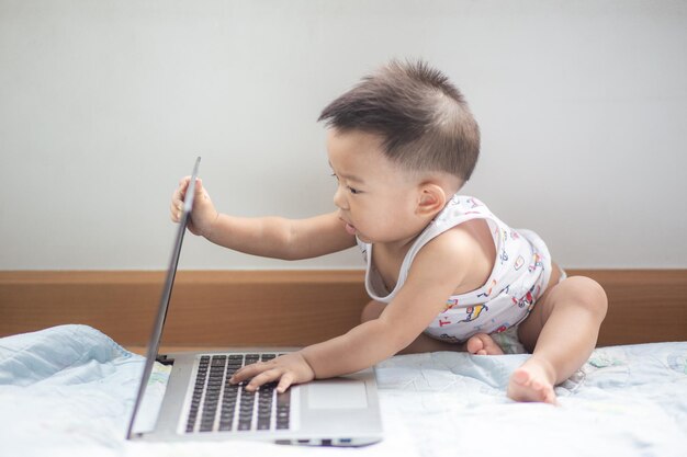 La longitud completa del bebé jugando con la computadora portátil en casa