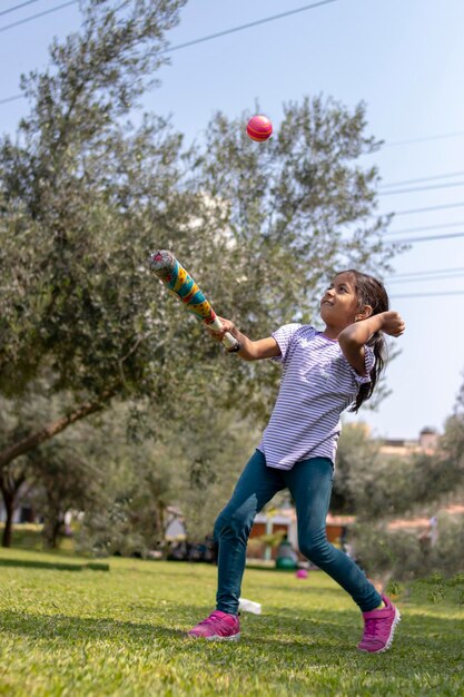 La longitud completa de la chica jugando con la pelota al aire libre