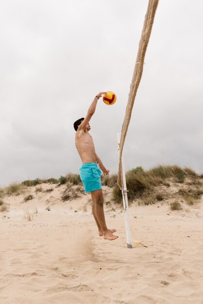 longitud completa de hombre sin camisa sosteniendo un paraguas en la playa