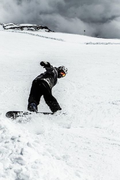 La longitud completa del hombre haciendo snowboard en la nieve