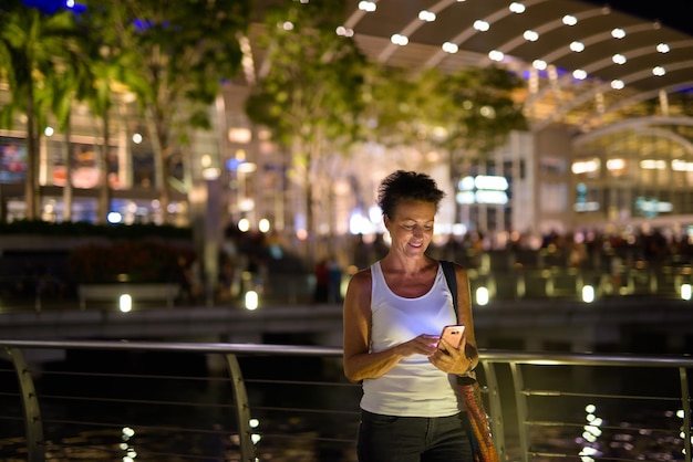 Foto longitud completa de hombre sonriente de pie en la ciudad por la noche