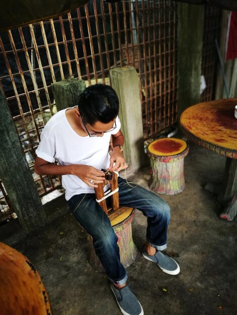 Foto longitud completa de un joven sentado en una silla