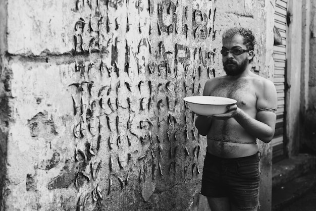 Foto longitud completa de un joven sosteniendo un cuenco de agua contra la pared