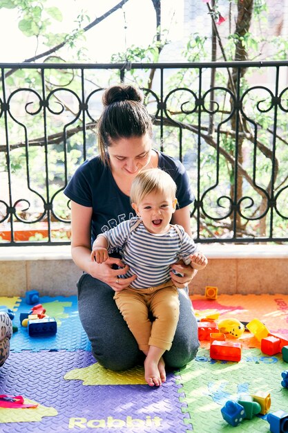 Foto la longitud completa de la madre y la hija sentadas en el suelo