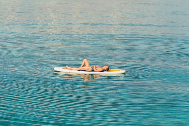 Foto longitud completa de mujer acostada en una tabla de surf en el mar