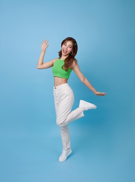 Foto longitud completa mujer asiática feliz sonriendo y saltando mientras celebra el éxito