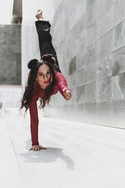 Foto la longitud completa de la mujer bailando en el suelo contra la pared