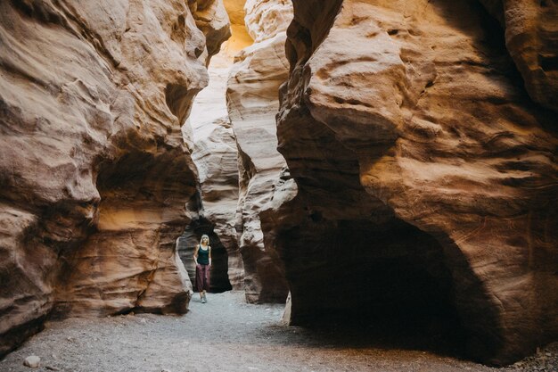 Foto la longitud completa de la mujer caminando en la formación rocosa en la cueva