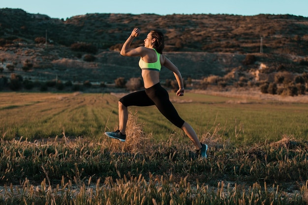 La longitud completa de la mujer con corriendo en el campo