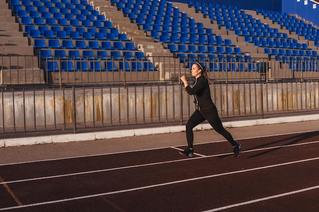 La longitud completa de la mujer corriendo en el estadio