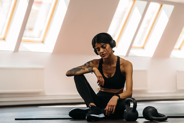 La longitud completa de la mujer descansando en el gimnasio