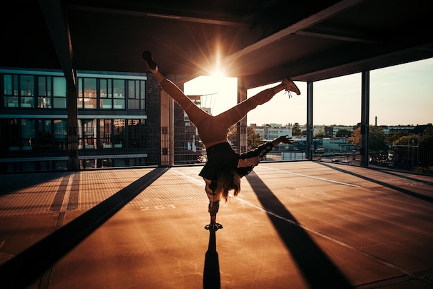 Longitud completa de una mujer haciendo handstand en el interior durante la puesta de sol