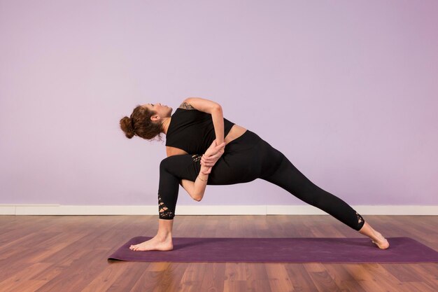 Foto la longitud completa de la mujer haciendo yoga en el suelo de madera dura