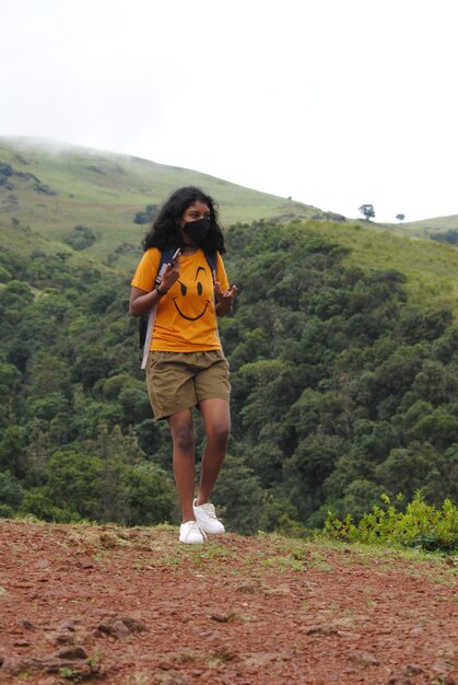 Foto la longitud completa de una mujer joven de pie en la montaña contra el cielo