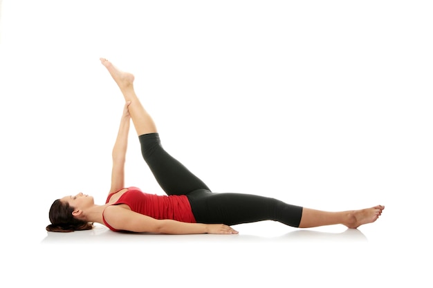 longitud completa de una mujer joven practicando yoga sobre un fondo blanco
