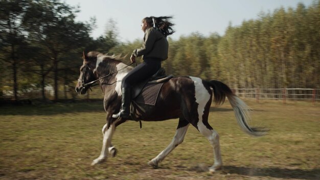 La longitud completa de la mujer montando a caballo en el campo