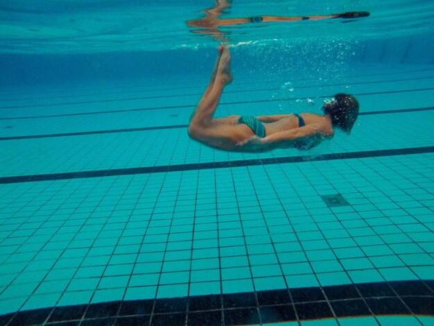 La longitud completa de la mujer nadando en la piscina