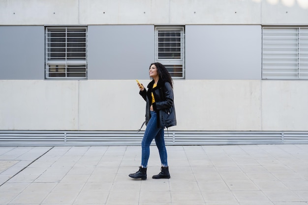 Foto la longitud completa de la mujer de pie en la acera contra la pared