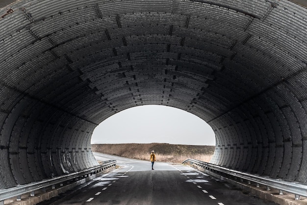 Foto la longitud completa de la mujer de pie en la carretera bajo el túnel