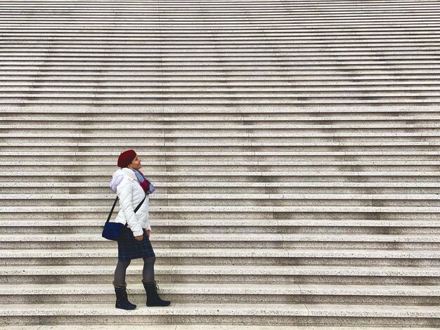 Foto la longitud completa de la mujer de pie en las escaleras anchas