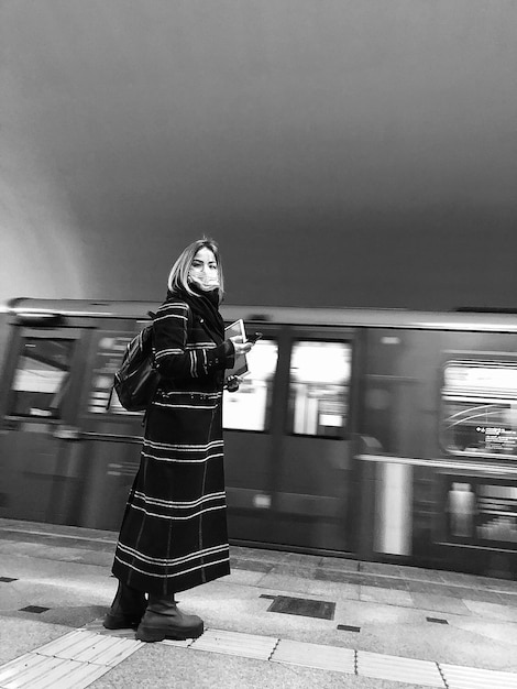 La longitud completa de la mujer de pie en la estación de tren