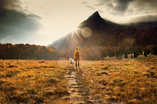 Foto la longitud completa de la mujer de pie con el perro en el campo