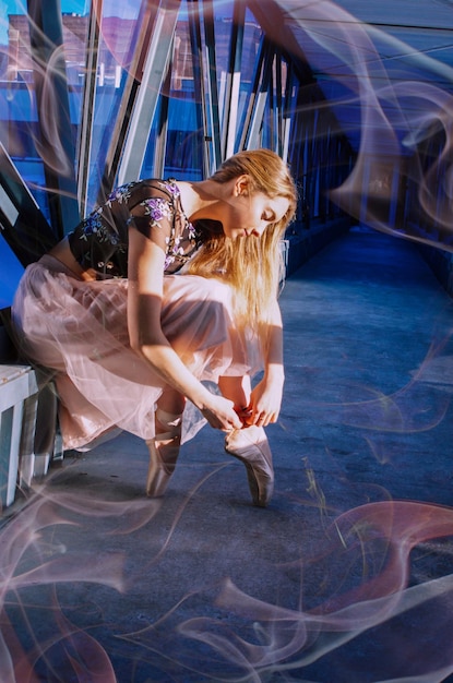 La longitud completa de la mujer que usa zapatos de ballet mientras está sentada en el corredor del edificio