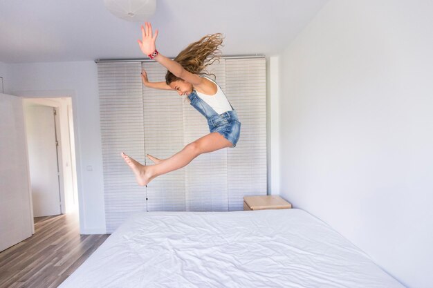 Foto la longitud completa de la mujer saltando en la cama en casa