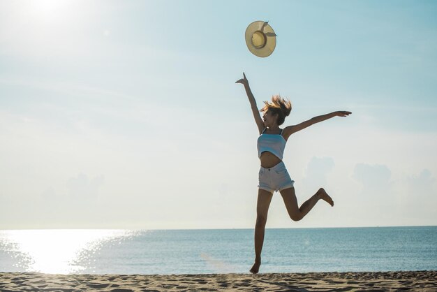 Foto la longitud completa de la mujer saltando en la playa contra el cielo