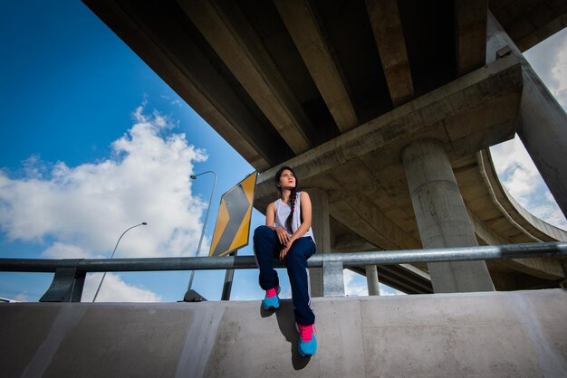 Foto la longitud completa de la mujer sentada en la barandilla bajo el puente