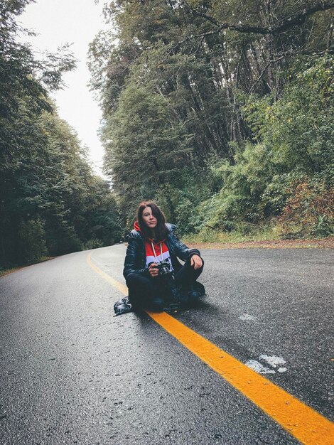 Foto la longitud completa de la mujer sentada en la carretera