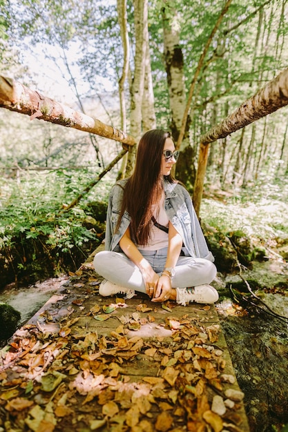 Foto la longitud completa de la mujer sentada junto al árbol en el bosque
