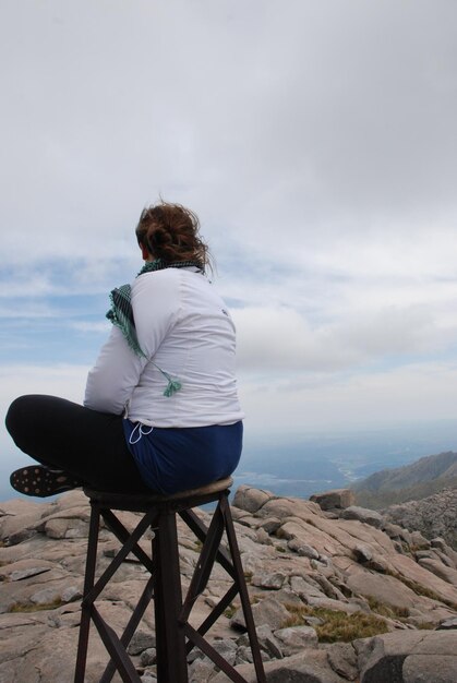 Foto la longitud completa de la mujer sentada en un taburete contra el cielo