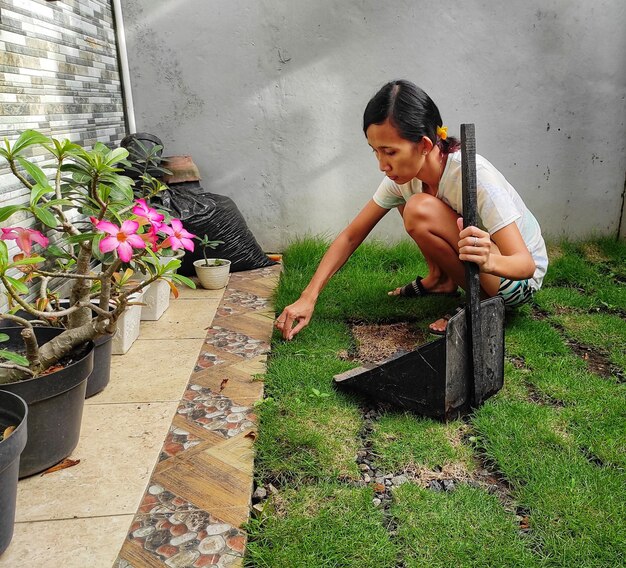 Foto la longitud completa de la mujer sosteniendo una flor mientras está de pie en la planta