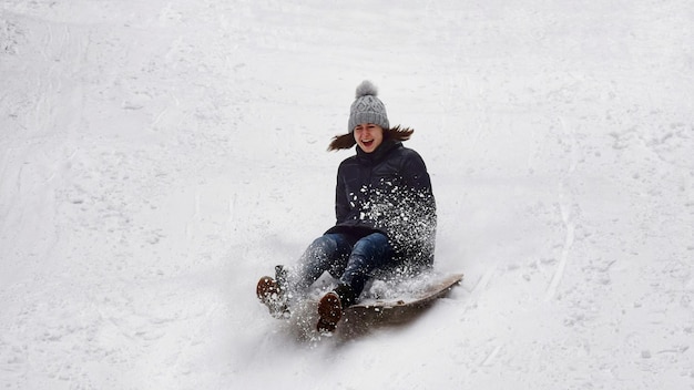 La longitud completa de una mujer en trineo en un campo cubierto de nieve