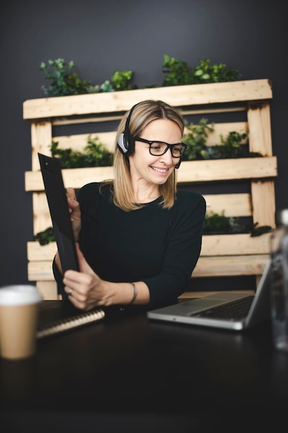 Foto la longitud completa de la mujer usando el teléfono mientras está sentada en la mesa