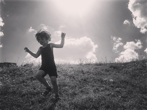 Foto la longitud completa del niño en el campo contra el cielo