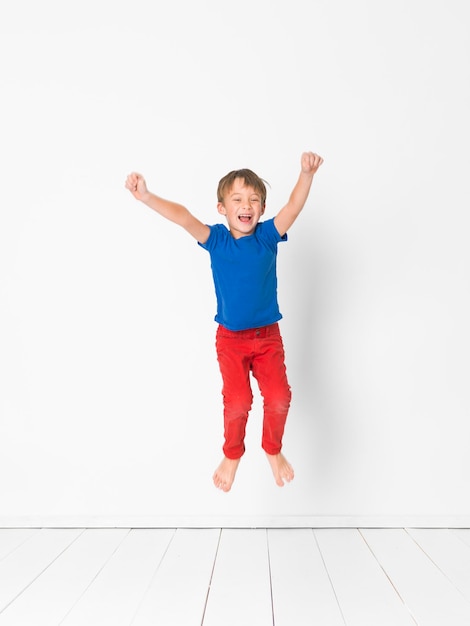 Foto longitud completa de un niño feliz saltando contra un fondo blanco