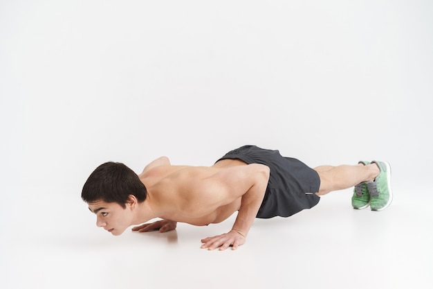 Longitud total de un deportista en forma saludable haciendo ejercicios de plancha sobre blanco