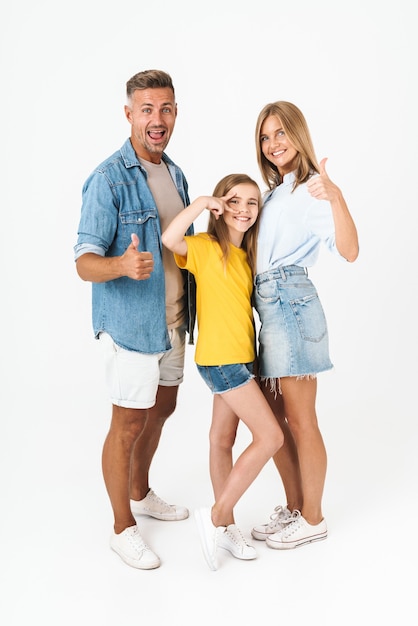 Longitud total de hermosa familia caucásica mujer y hombre con niña sonriendo y mostrando los pulgares para arriba aislado en blanco