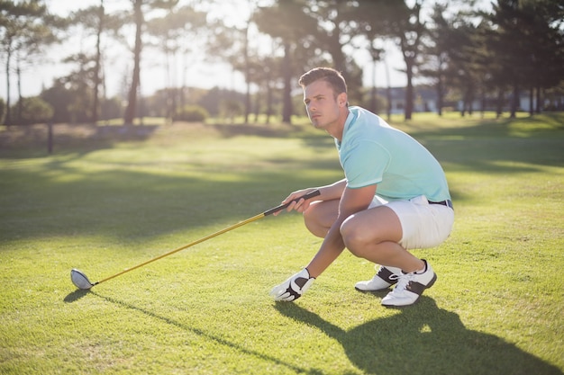 Longitud total del hombre golfista colocando la pelota de golf en el tee