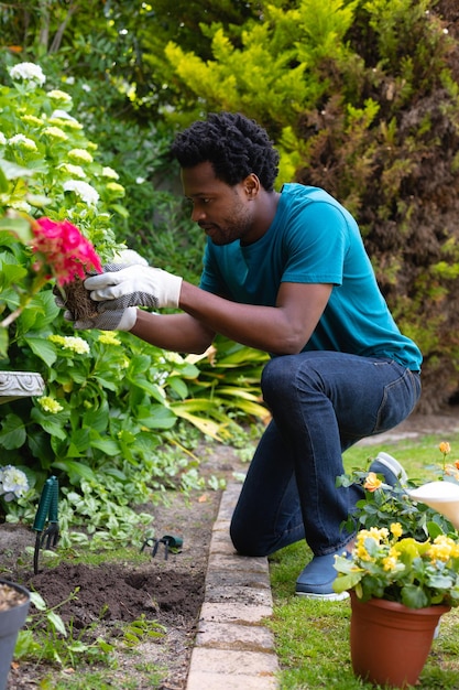 Longitud total del joven afroamericano arrodillado mientras trabaja en el jardín en el patio trasero