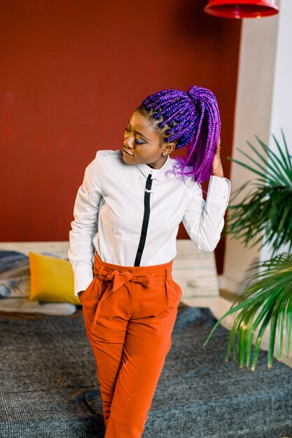 Longitud total de mujer atractiva con cabello azul en ropa elegante. Modelo de moda femenina africana